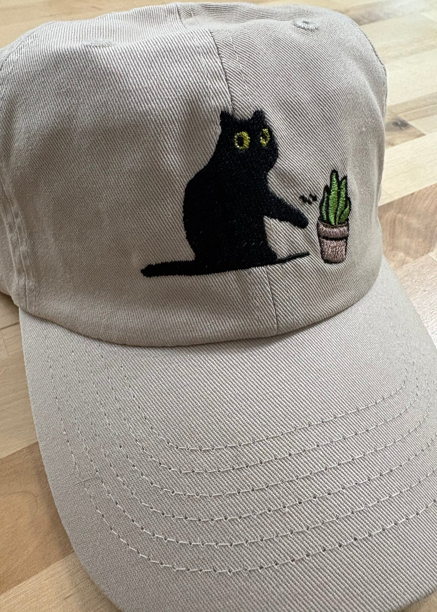 Cat knocking over plant embroidered on ran dad hat