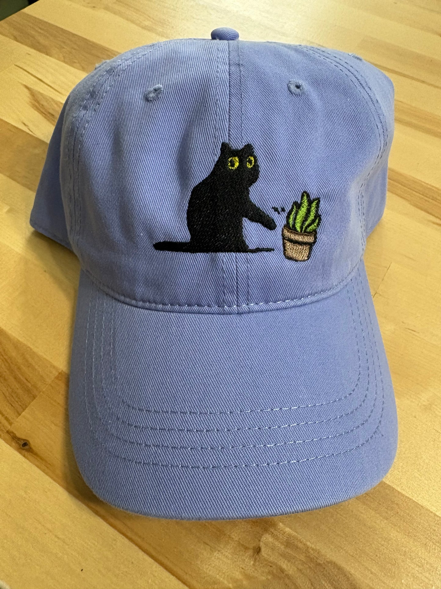 Cat knocking over plant embroidered on light purple cotton dad hat