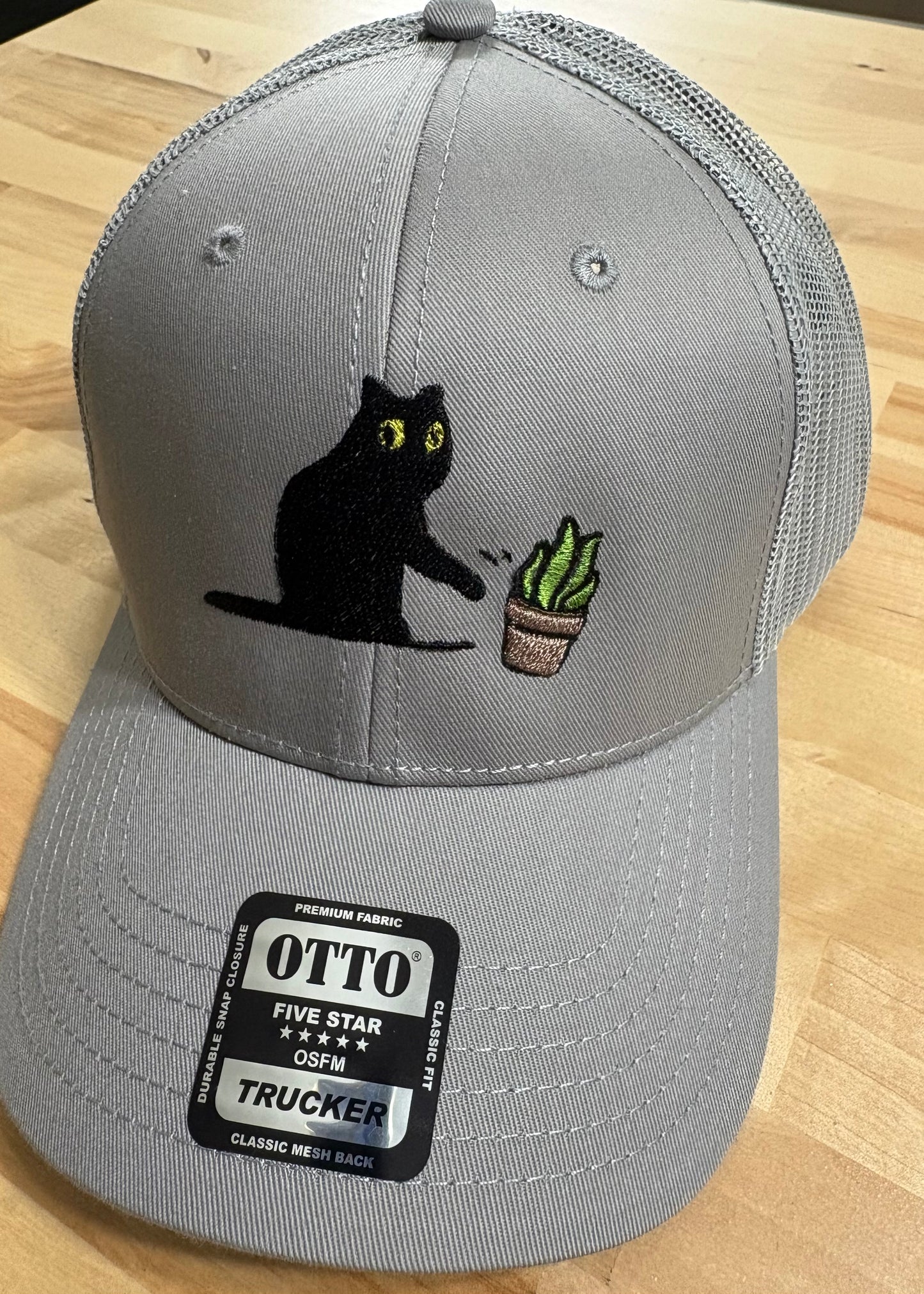 Cat knocking over plant embroidered on light grey Otto trucker hat