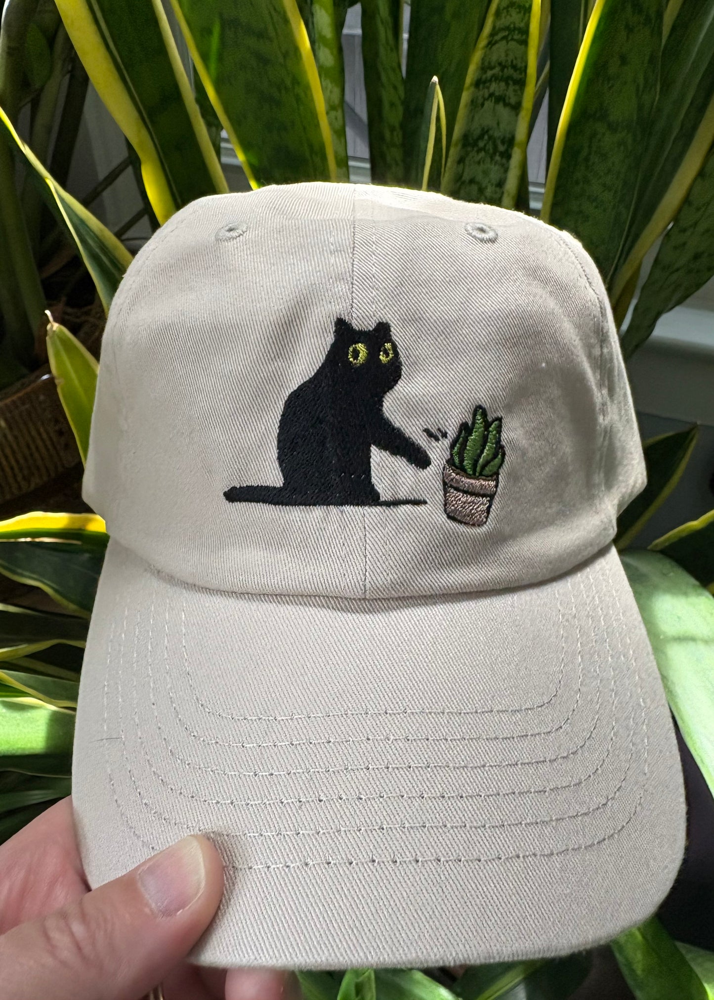 Cat knocking over plant embroidered on ran dad hat