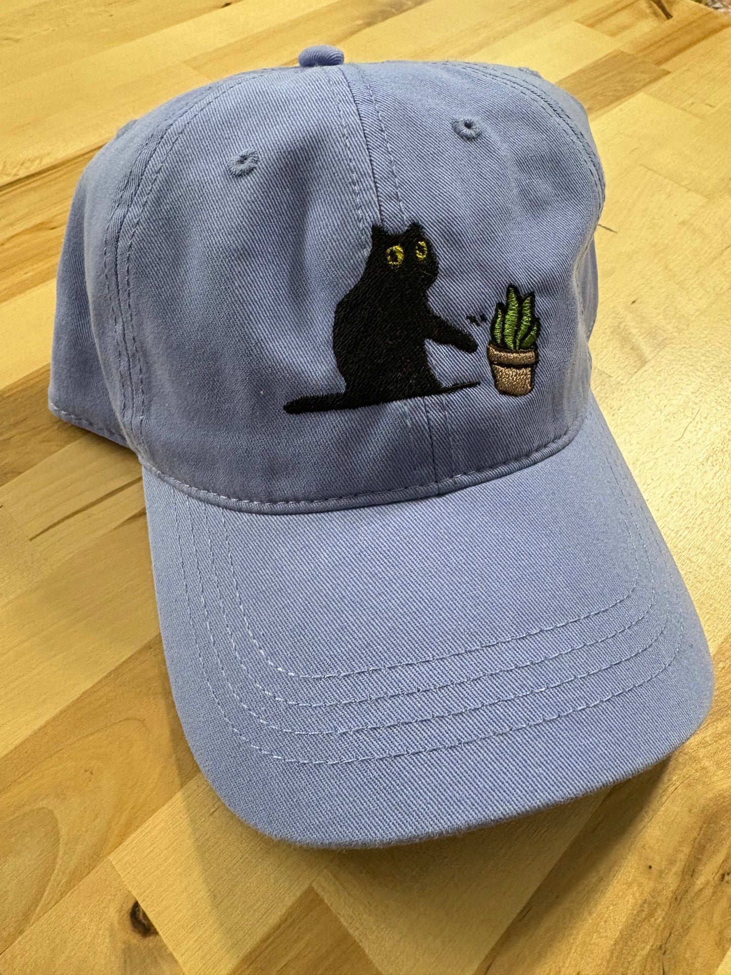 Cat knocking over plant embroidered on light purple cotton dad hat