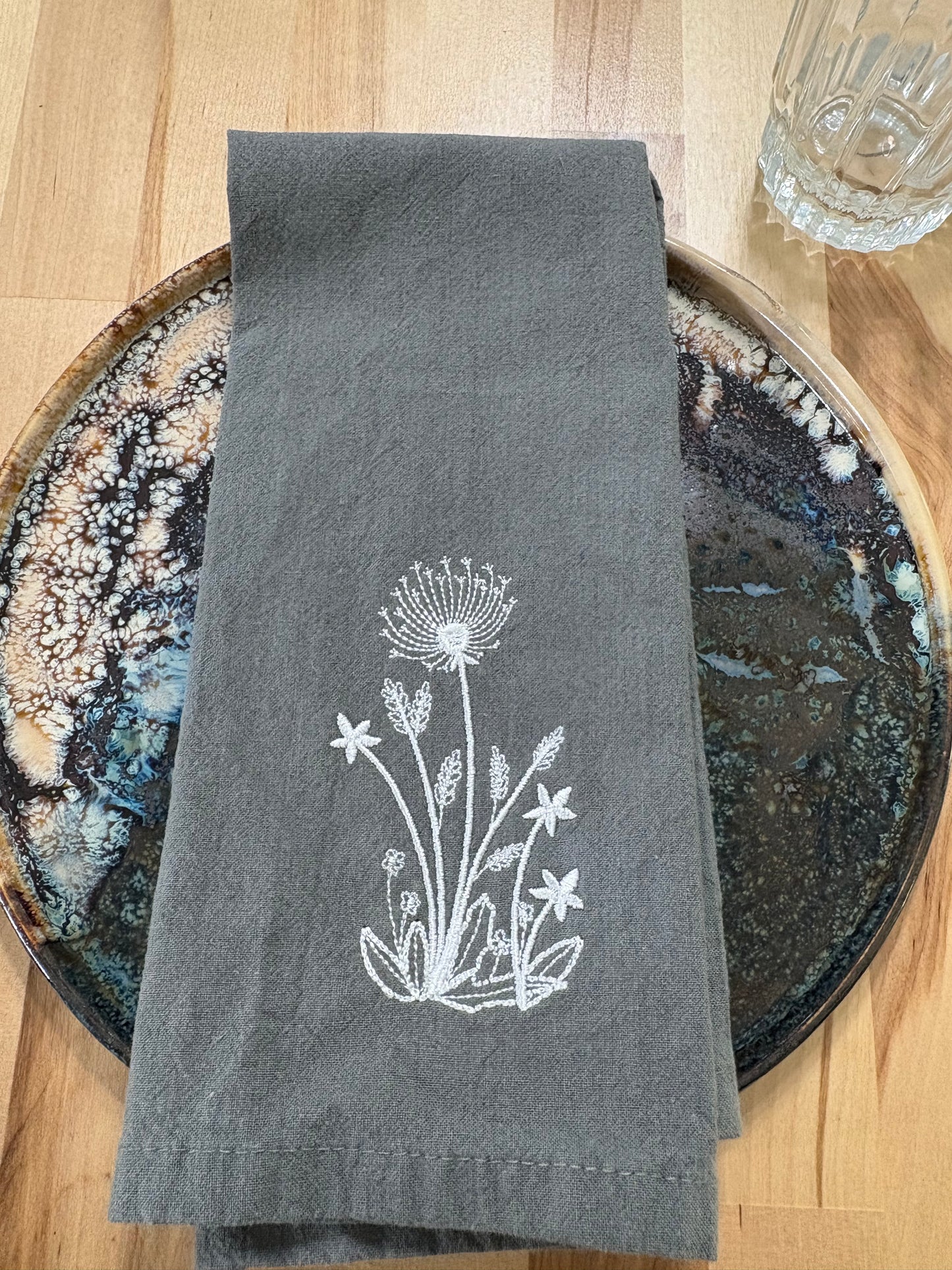 White dandelion embroidered on grey napkin