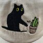 Cat knocking over plant embroidered on ran dad hat
