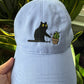Cat knocking over plant embroidered on light purple cotton dad hat