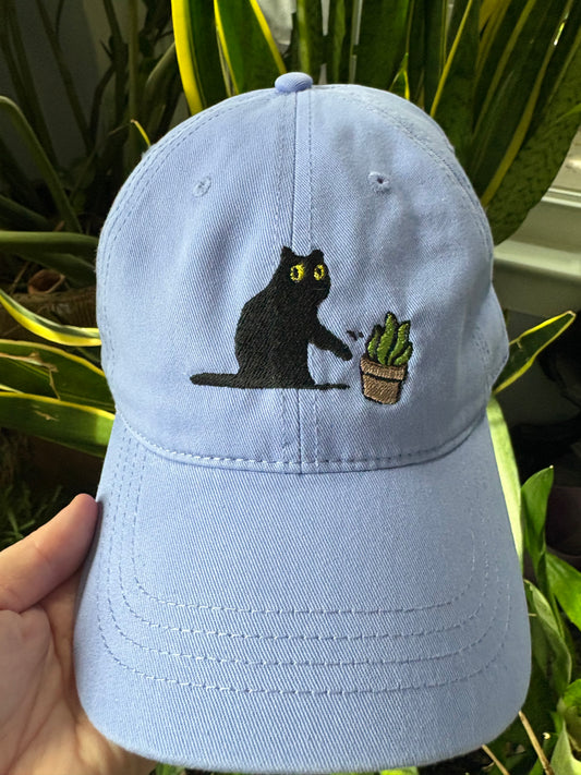 Cat knocking over plant embroidered on light purple cotton dad hat