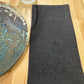 Delicate bee embroidered on black napkin with black thread