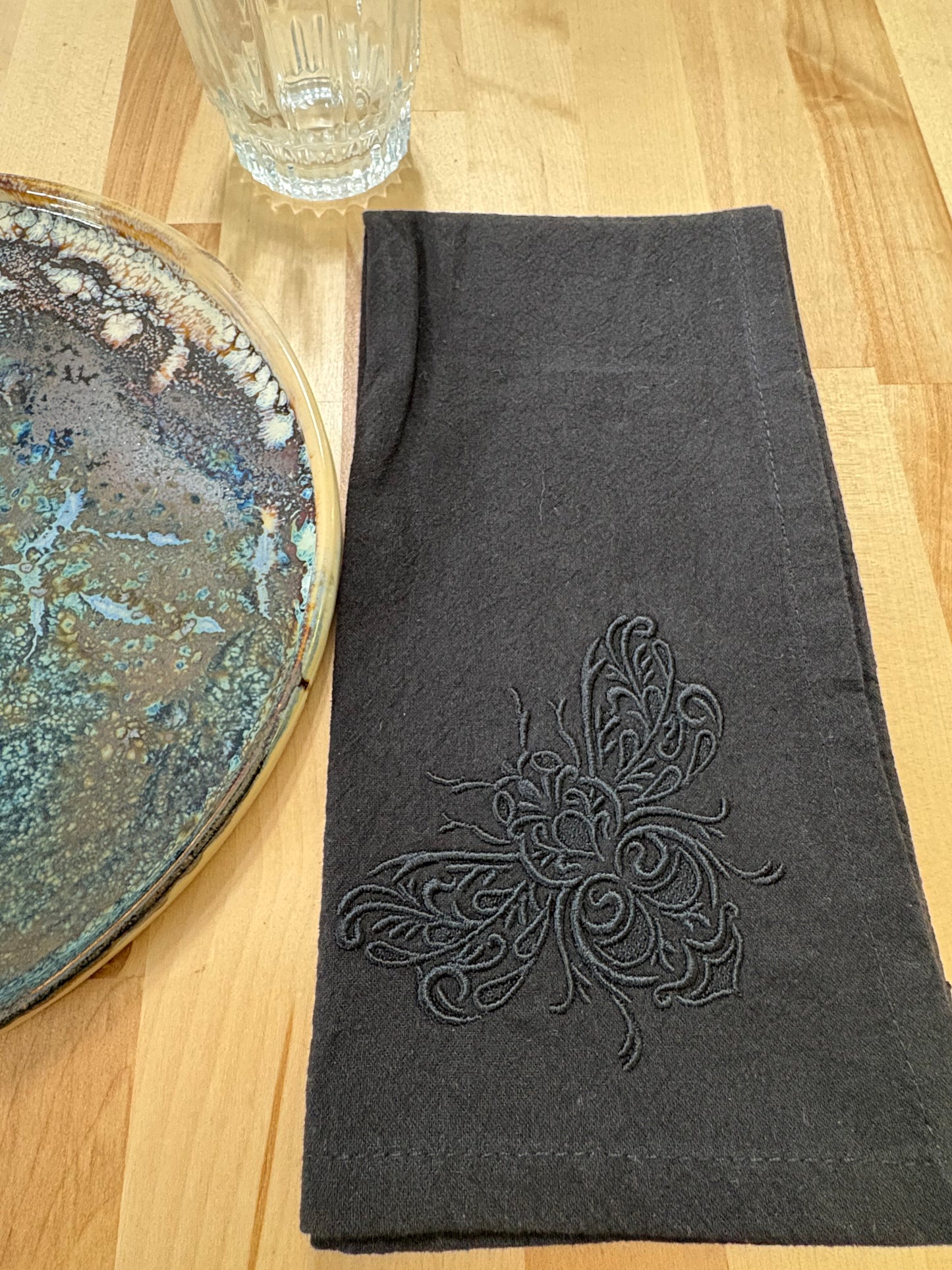Delicate bee embroidered on black napkin with black thread
