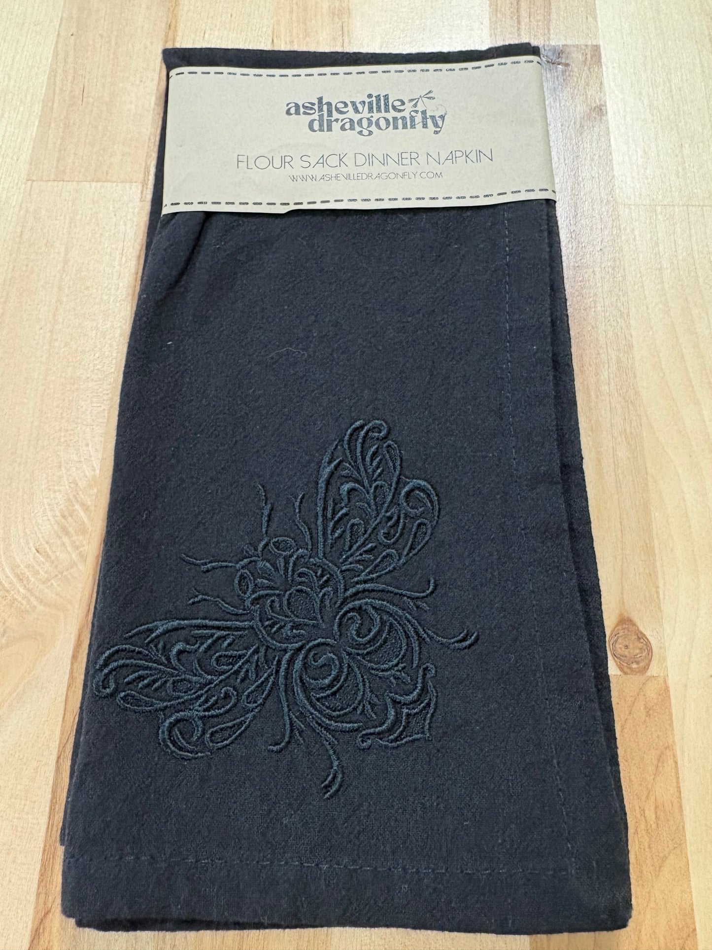 Delicate bee embroidered on black napkin with black thread