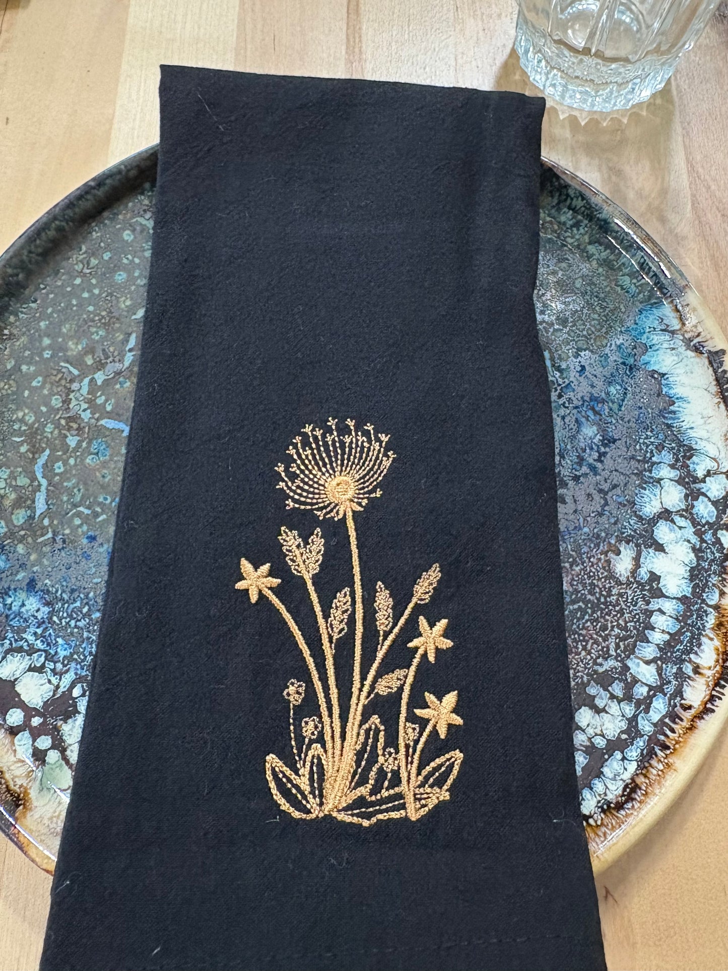 Black cotton napkin with gold embroidered dandelion