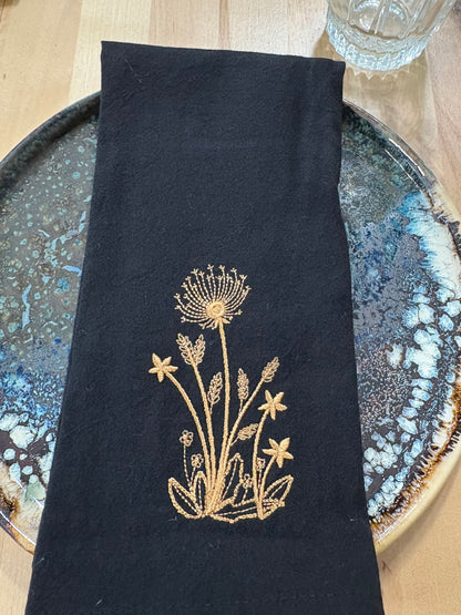 Black cotton napkin with gold embroidered dandelion