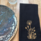 Black cotton napkin with gold embroidered dandelion