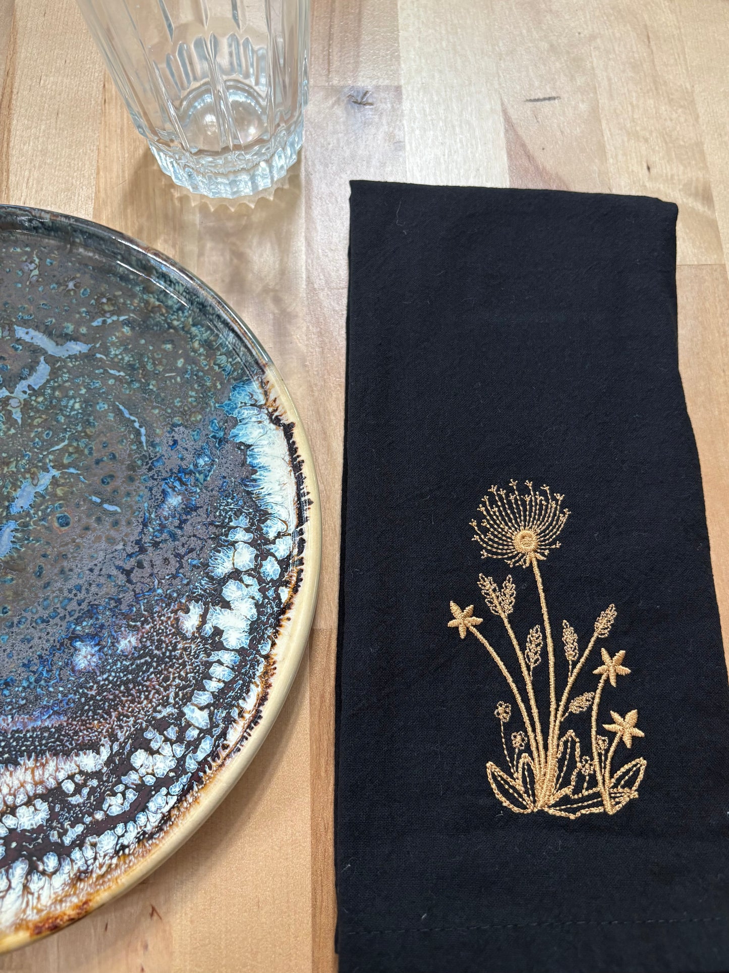 Black cotton napkin with gold embroidered dandelion