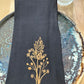 Black cotton napkin with gold embroidered goldenrod
