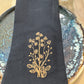 Black embroidered napkin with gold embroidered daisies