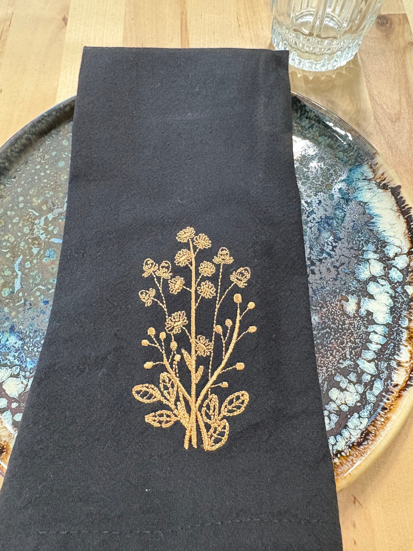Black embroidered napkin with gold embroidered daisies