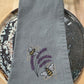 Gray napkin with embroidered bees and lavender on a wooden surface