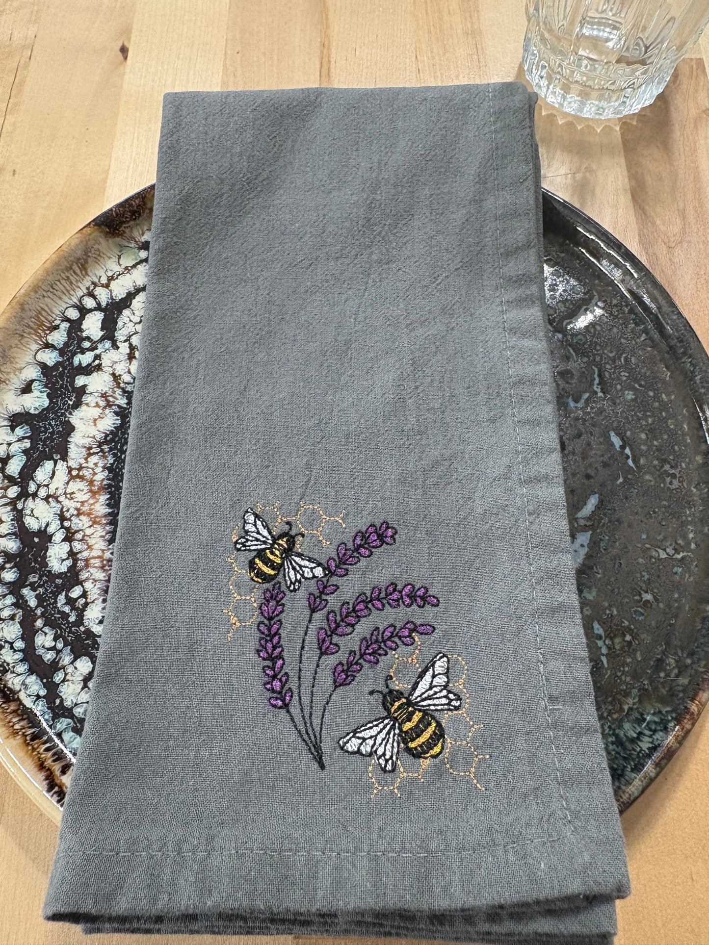 Gray napkin with embroidered bees and lavender on a wooden surface