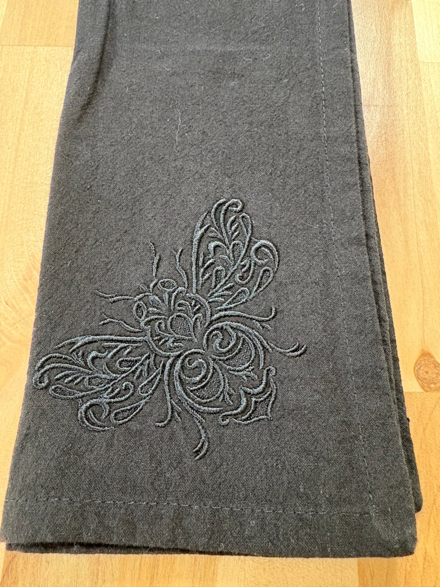 Delicate bee embroidered on black napkin with black thread