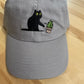 Cat knocking over plant embroidered on light grey dad hat