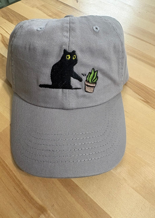 Cat knocking over plant embroidered on light grey dad hat