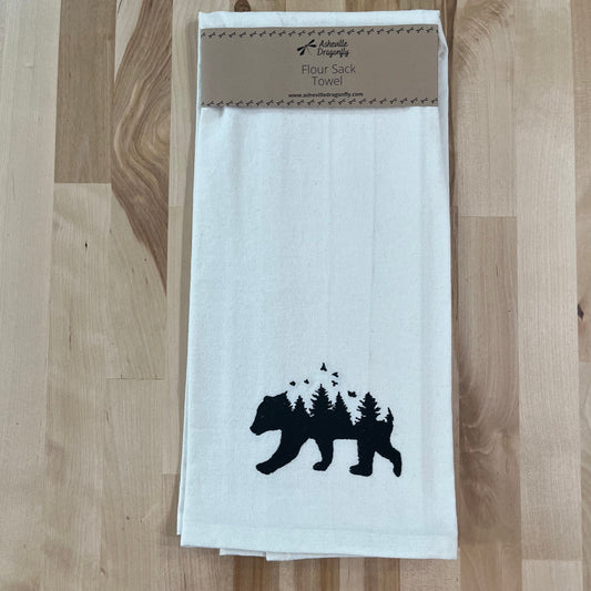 A white kitchen towel with black embroidery of a bear and trees on the lower part.