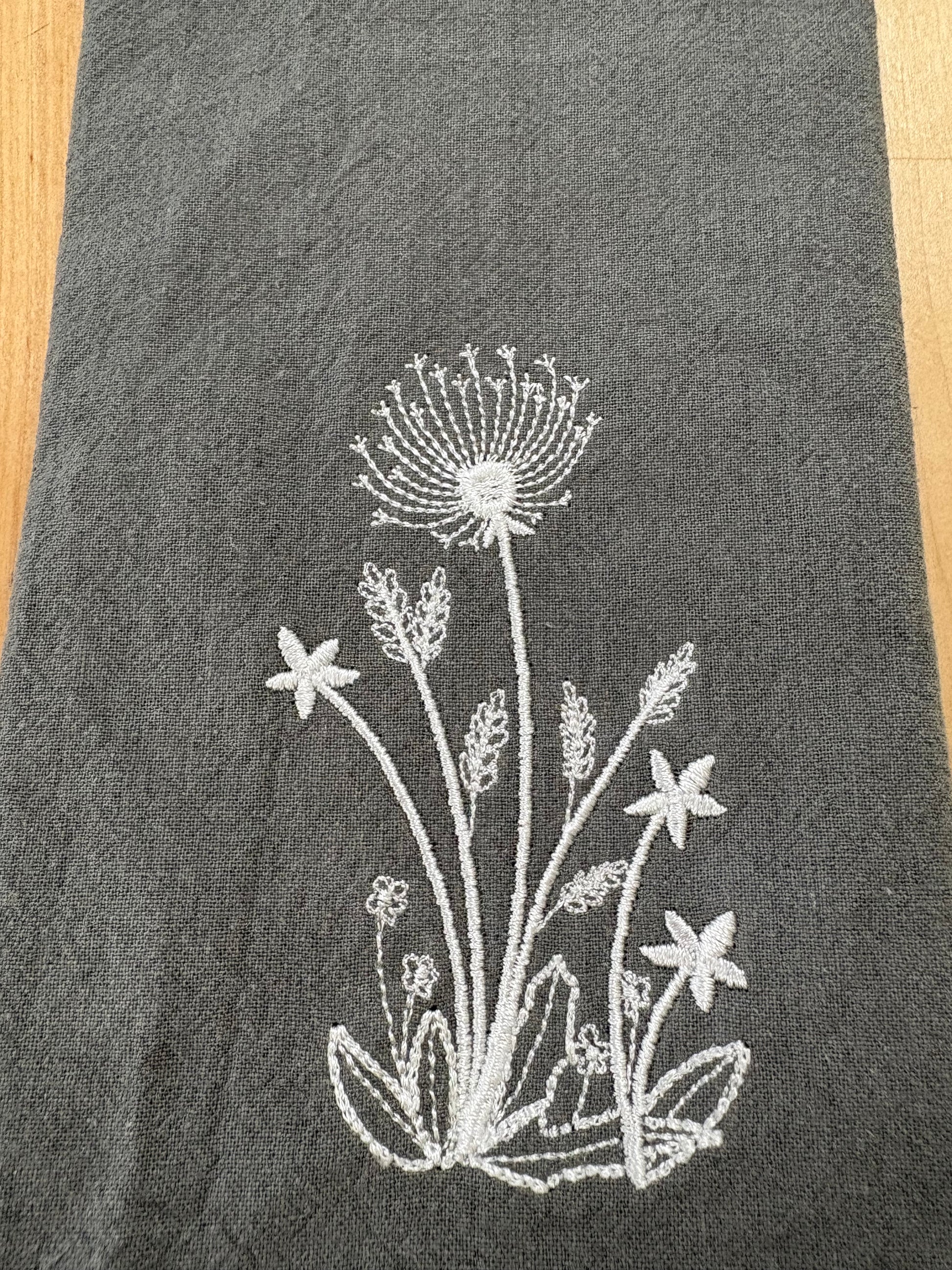 White dandelion embroidered on grey napkin