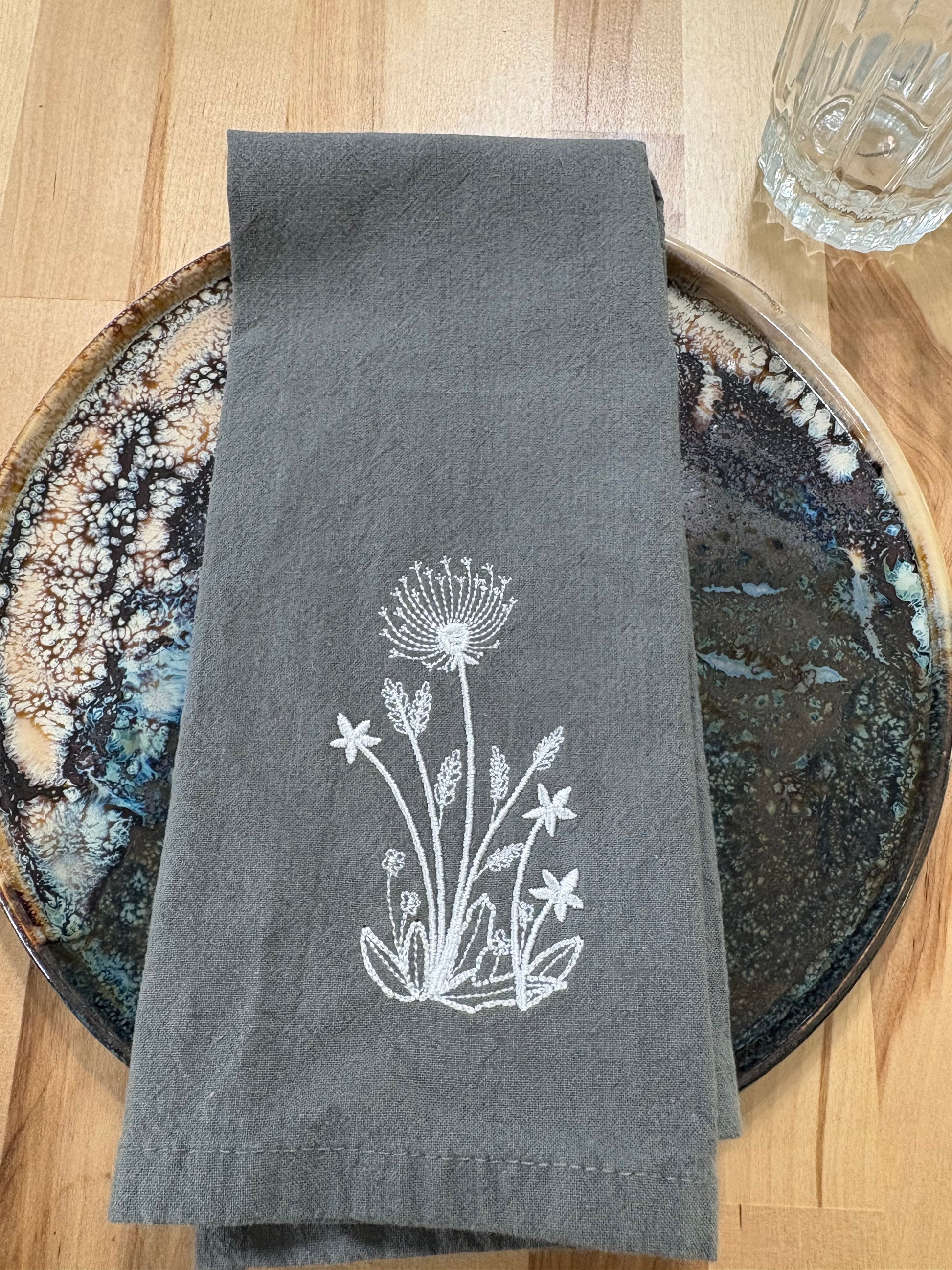 White dandelion embroidered on grey napkin