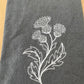 White thistle embroidered on grey napkin