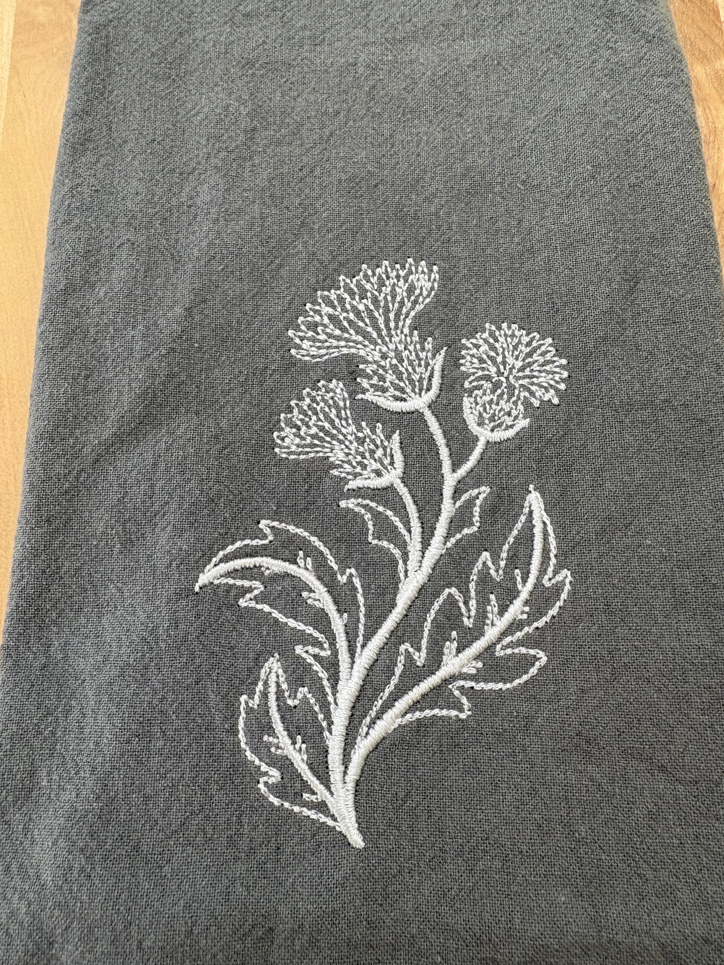 White thistle embroidered on grey napkin