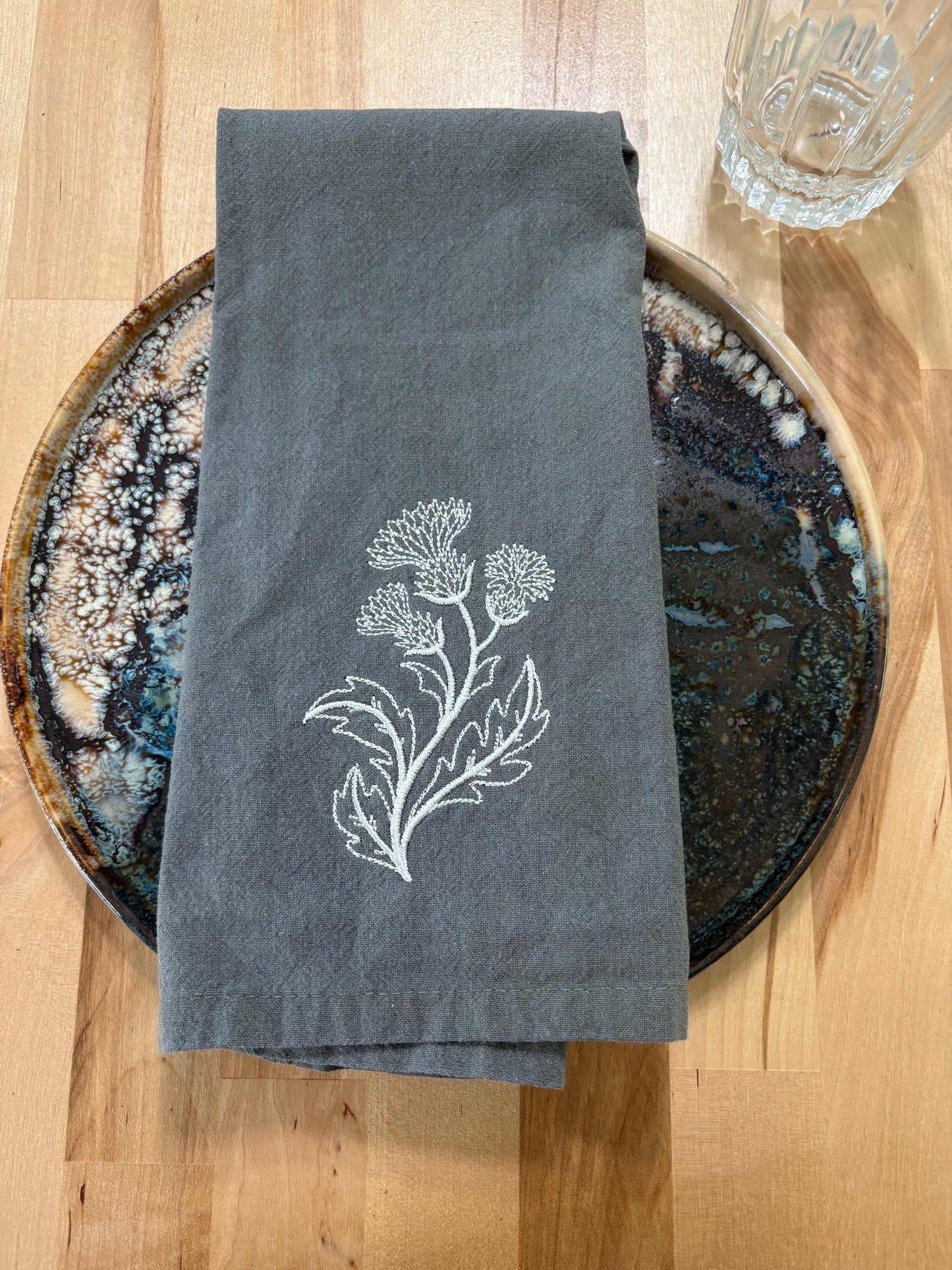 White thistle embroidered on grey napkin
