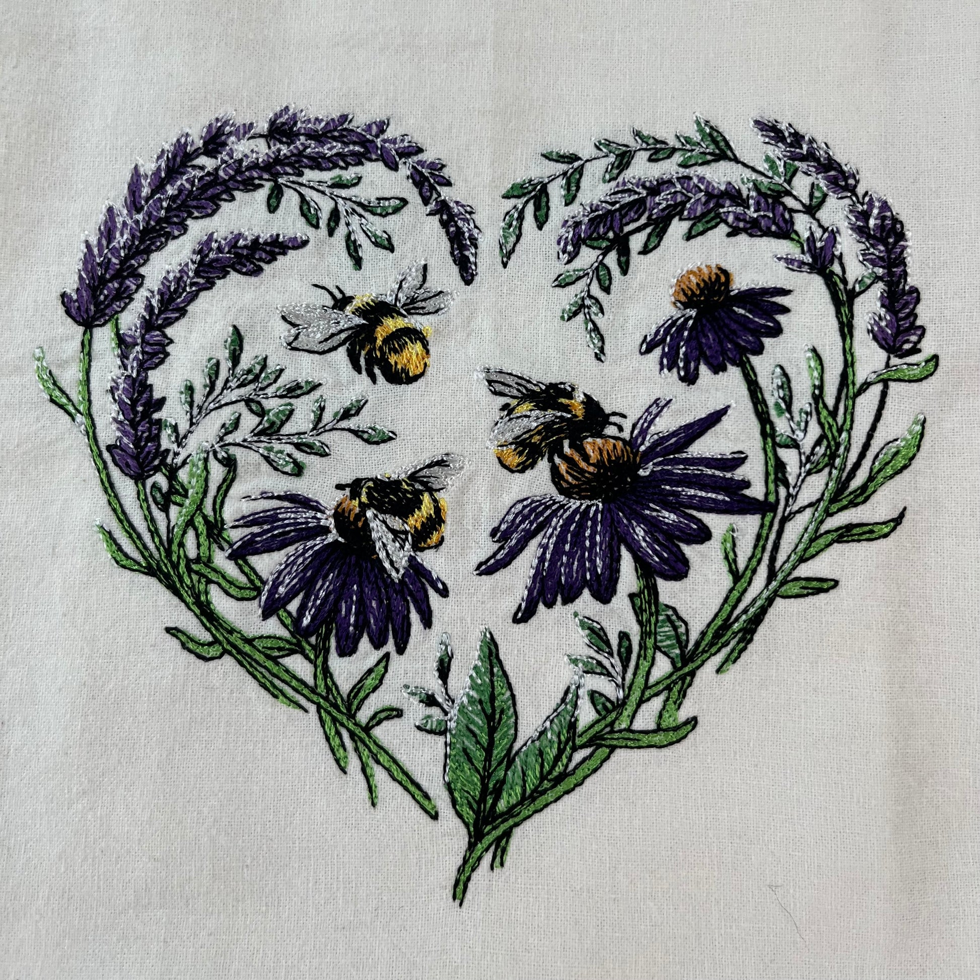 Close up of a floral heart with buzzing bees embroidered on an organic flour sack towel