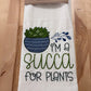 Embroidered towel with a yucca plant design and text on a wooden surface