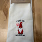 Embroidered towel with gnome design and text on a wooden surface