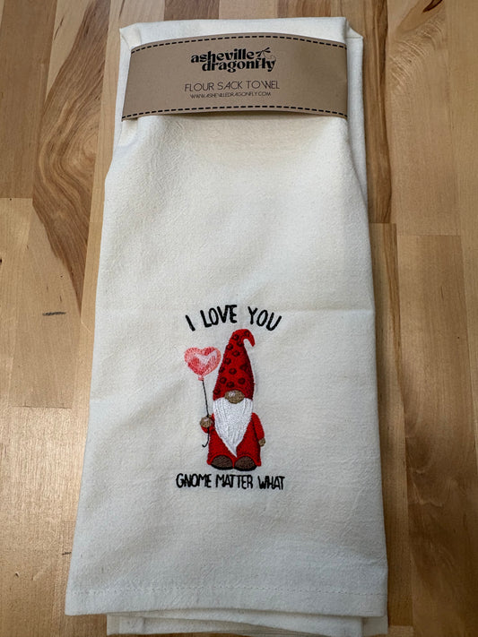 Embroidered towel with gnome design and text on a wooden surface