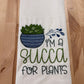 White towel with a graphic of a succulent and text on a wooden surface