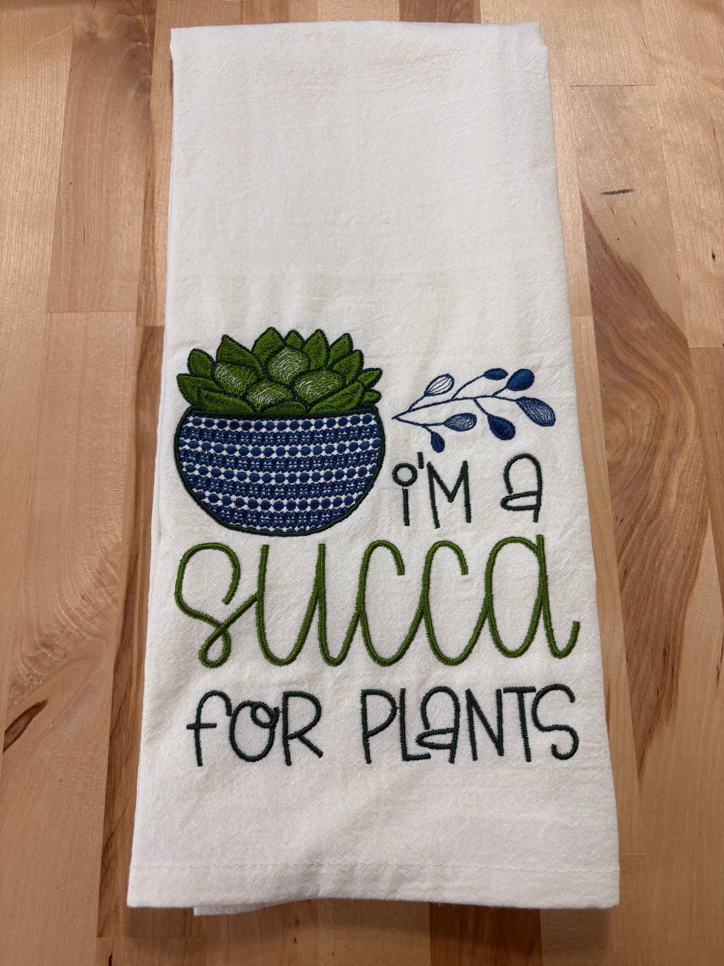 White towel with a graphic of a succulent and text on a wooden surface